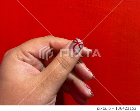 Female hand with red bow nail art on silver manicure background Female hand with red bow nail art on silver manicure background 136422152