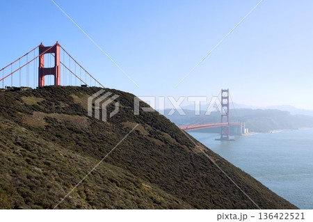 Golden Gate Bridge behind green hill on clear day 136422521