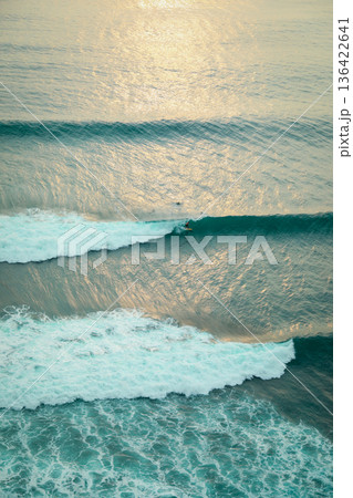 Surfers catch waves as the sun sets on the ocean in Bali Surfers catch waves as the sun sets on the ocean in Bali 136422641