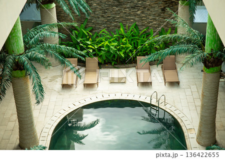 People enjoy sun loungers and a pool surrounded by greenery 136422655