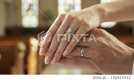 結婚指輪をつけたウェディング姿の日本人新郎新婦が重ね合わせた手のクローズアップ 136423412