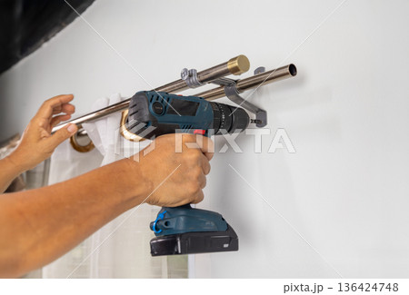 Handyman repairman hanging and fixing the curtain rod on the window 136424748