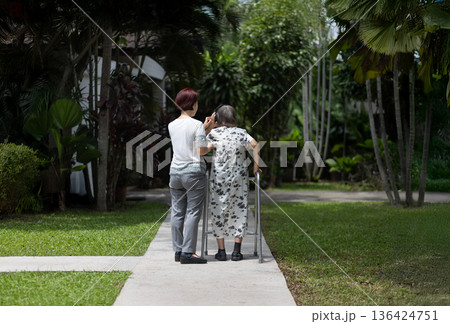 Elderly woman exercise walking in backyard with daughter. 136424751