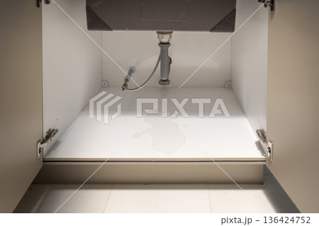 Plumber fixing drain pipe leak under sink. 136424752