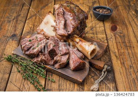 Tender slow cooked veal ossobuco with juicy meat pieces bone marrow herbs on wooden background 136424783