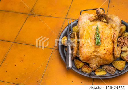 Homemade roast chicken with potatoes baked in pan. Traditional comfort food on warm yellow background, overhead food photography 136424785