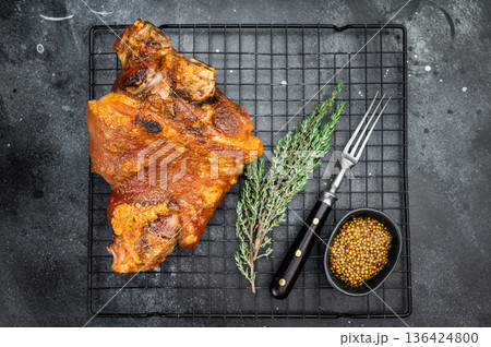 Oven roasted pork shank showing crispyskin, seared surface and gelatin rich structure served on grillrack with aromatic herbs and spices. Oven roasted pork shank showing crispyskin, seared surface and gelatin rich structure served on grillrack with aromatic herbs and spices. 136424800