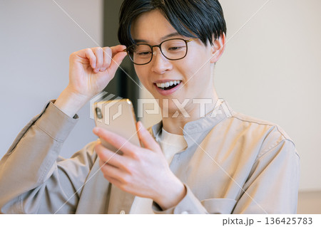 カフェでスマホを使うメガネをかけた男性 136425783