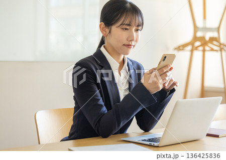 スマホを操作する若いビジネスウーマン スマホを操作する若いビジネスウーマン 136425836