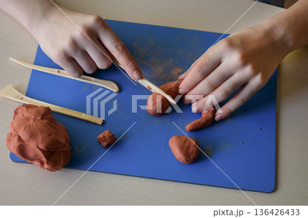 Children clay sculpting master class flat lay step 5 connecting separate parts and smoothing surface creative educational handmade craft process 136426433
