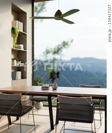 Wooden table and armchairs under ceiling fan aside bookshelf and window wall with a mountain scenery 136427327