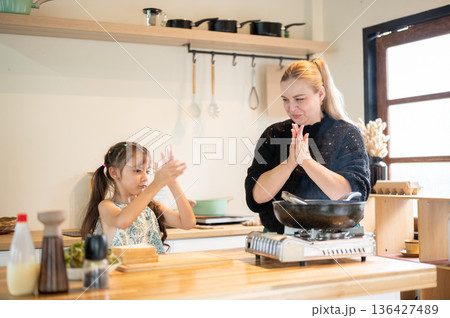 Asian daughter clapping with caucasian white mother learn to make sandwich at kitchen cooking counter. Asian daughter clapping with caucasian white mother learn to make sandwich at kitchen cooking counter. 136427489