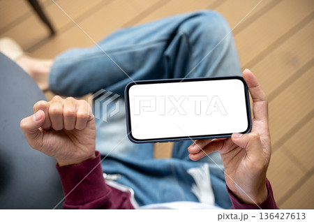 A man's hand holding blank screen smartphone making a fist in excited while sitting at table in cafe 136427613