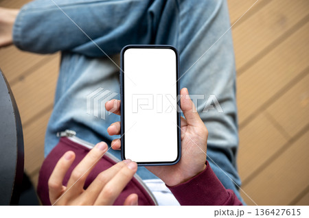 A man holding and touching on blank screen smartphone while sitting at table in cafe or coffee shop. A man holding and touching on blank screen smartphone while sitting at table in cafe or coffee shop. 136427615
