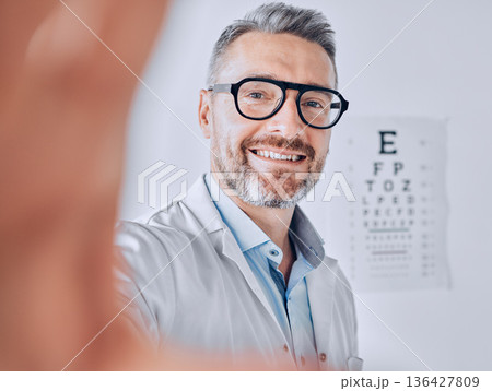 Selfie, glasses and eye exam with an optometrist man in his office for healthcare or vision improvement. Medical, portrait and eyewear with a doctor or optician in a clinic for assessment and testing Selfie, glasses and eye exam with an optometrist man in his office for healthcare or vision improvement. Medical, portrait and eyewear with a doctor or optician in a clinic for assessment and testing 136427809