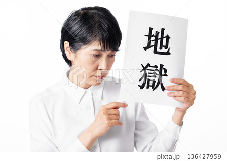 地獄と書かれた紙を持ち悲しそうに俯くシニア女性 地獄と書かれた紙を持ち悲しそうに俯くシニア女性 136427959