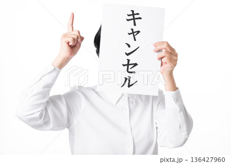 キャンセルと書かれた紙を持つ白いシャツを着た人物 136427960