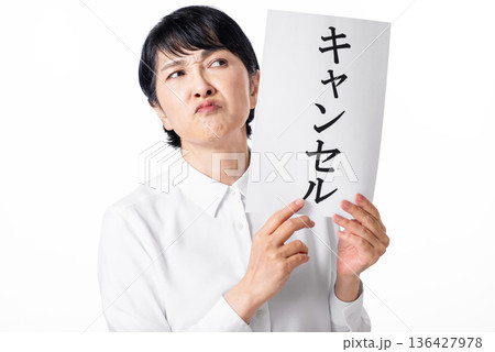 キャンセルと書かれた紙を持ち険しい表情のシニア女性 キャンセルと書かれた紙を持ち険しい表情のシニア女性 136427978
