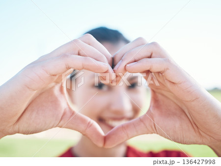 Heart shape, closeup and hands of woman with a care, sweet and cute gesture outdoor on a field. Happy, smile and zoom of a young female person with a love sign or emoji in a outside park or garden. 136427998