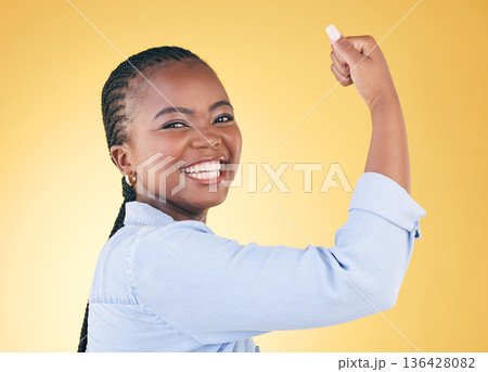 Portrait, black woman and flex for power, smile and challenge on a yellow studio background. Face, happy person and model with strength, arm muscle and achievement with success, confident and winning 136428082