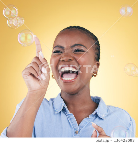 Excited, laugh and black woman on yellow background with bubbles for happiness, joy and have fun. Happy, smile and isolated African person in studio pop soap bubble for playful magic and color Excited, laugh and black woman on yellow background with bubbles for happiness, joy and have fun. Happy, smile and isolated African person in studio pop soap bubble for playful magic and color 136428095