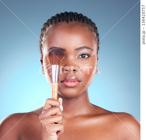 Studio portrait, black woman and brush for makeup powder application, facial foundation or beauty routine. Cosmetics product, cosmetology tools and African female model on blue gradient background Studio portrait, black woman and brush for makeup powder application, facial foundation or beauty routine. Cosmetics product, cosmetology tools and African female model on blue gradient background 136428757