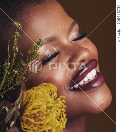 Face, beauty and protea with the smile of a black woman in studio on brown background for natural treatment. Happy, plant or cosmetics and a young model indoor for aesthetic wellness with flowers 136428759