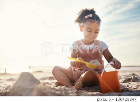 Sun flare, beach and happy girl with sand, toys and vacation with happiness, playing and cheerful. Kid, shore and female child with fun, getaway trip and adventure with seaside holiday or development Sun flare, beach and happy girl with sand, toys and vacation with happiness, playing and cheerful. Kid, shore and female child with fun, getaway trip and adventure with seaside holiday or development 136428847