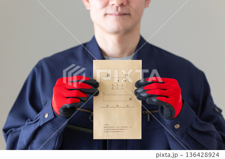 給料袋を持つ作業服のミドル男性ビジネスマン 136428924