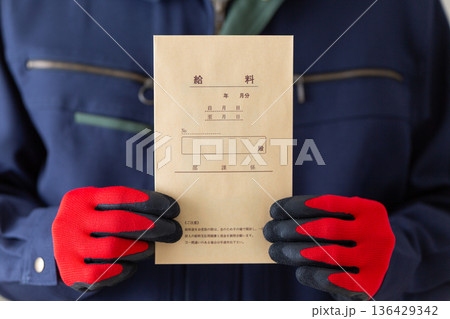 給料袋を持つ作業服のミドル男性ビジネスマン 136429342
