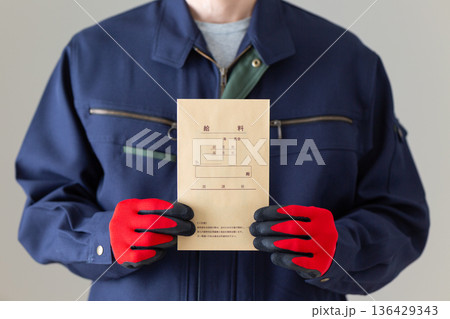 給料袋を持つ作業服のミドル男性ビジネスマン 136429343