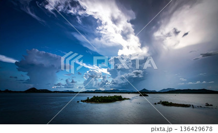 Dramatic storm clouds loom over a dark horizon as waves crash against the beach during a moody nature seascape at sunset Dramatic storm clouds loom over a dark horizon as waves crash against the beach during a moody nature seascape at sunset 136429678