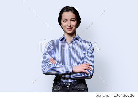 Portrait of smiling young confident girl looking at camera on white background 136430326