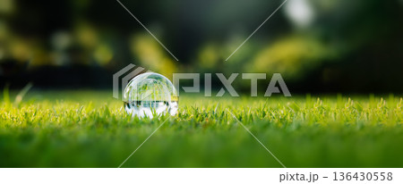 Crystal glass globe resting on green grass, concept for ecology and environment. Crystal glass globe resting on green grass, concept for ecology and environment. 136430558