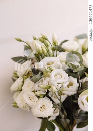 White carnation wed bouquet with wrapped stems leaning against white wall in sunlight White carnation wed bouquet with wrapped stems leaning against white wall in sunlight 136431478