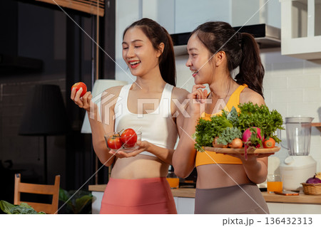 Two sporty women drinking green smoothie and eating fresh vegetables. Two sporty women drinking green smoothie and eating fresh vegetables. 136432313