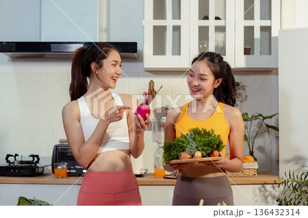 Two sporty women drinking green smoothie and eating fresh vegetables. Two sporty women drinking green smoothie and eating fresh vegetables. 136432314