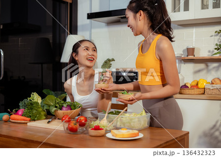 Two sporty women drinking green smoothie and eating fresh vegetables. Two sporty women drinking green smoothie and eating fresh vegetables. 136432323