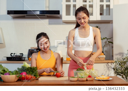 Two sporty women drinking green smoothie and eating fresh vegetables. Two sporty women drinking green smoothie and eating fresh vegetables. 136432333