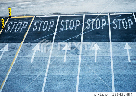 Stop signs and arrows painted on asphalt parking lot 136432494