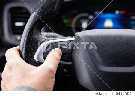Driver hand using steering wheel controls in modern vehicle Driver hand using steering wheel controls in modern vehicle 136432504