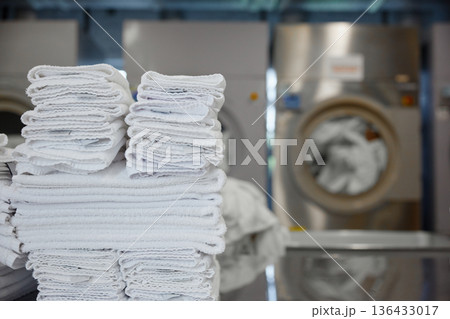 A stack of clean towels is on a table in front of a washing machine A stack of clean towels is on a table in front of a washing machine 136433017
