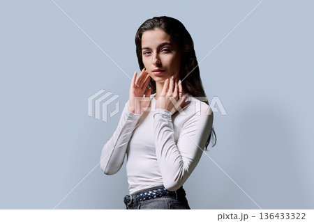 Portrait of beautiful fashionable young woman 18, 19 years old on gray background 136433322