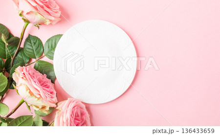 Pink roses arranged beside blank white plate on pastel pink background Banner Top view Copy space 136433659