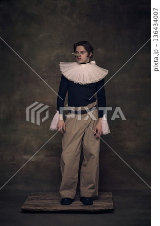 Young man with long nose in renaissance collar standing on wooden board. 136434007