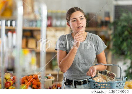 Woman in gray t-shirt in supermarket 136434066
