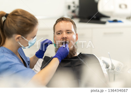 man sits in a chair at an appointment at a dental clinic man sits in a chair at an appointment at a dental clinic 136434087