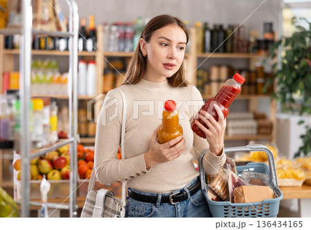 Young woman choosing juices in grocery store Young woman choosing juices in grocery store 136434165