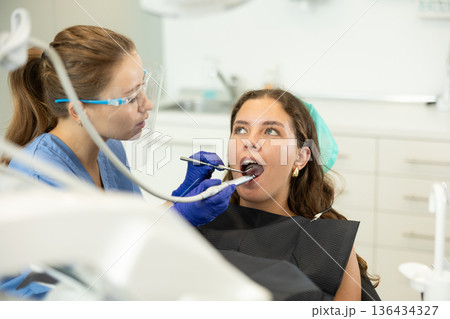 Woman dentist drilling and treating teeth of woman in clinic 136434327