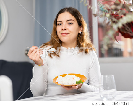 Emotional young woman eating rice at home Emotional young woman eating rice at home 136434351